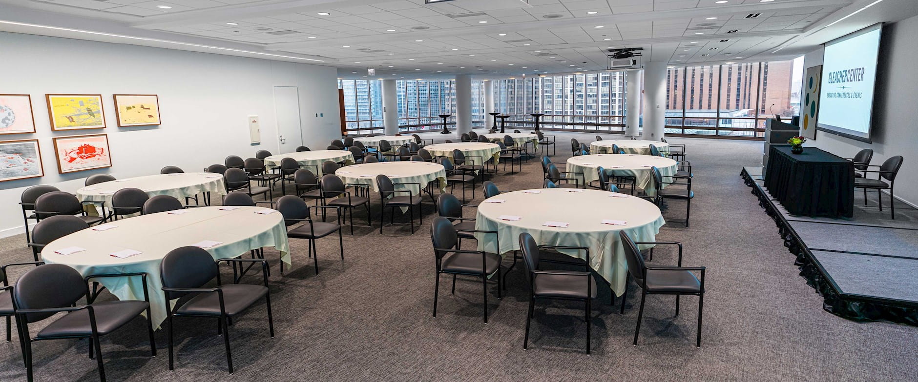 Gleacher Center dining room set for event with a presenter stage and table seating arrangements
