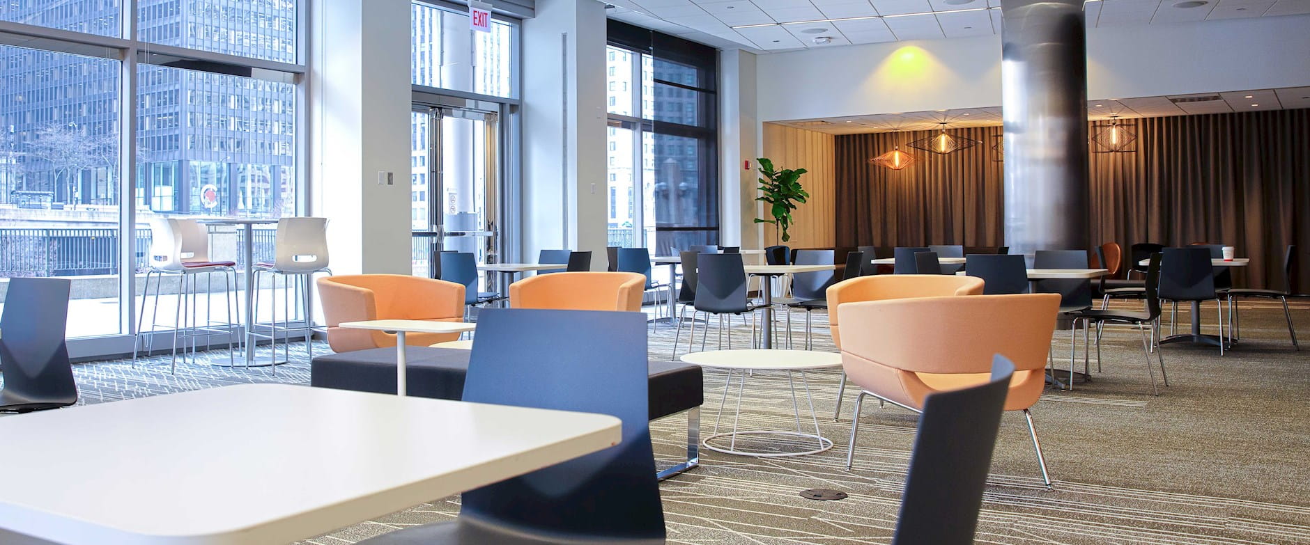 Lobby Lounge in Gleacher Center with a set of table and chairs toward a brown fabric feature wall and wall of floor-to-ceiling windows