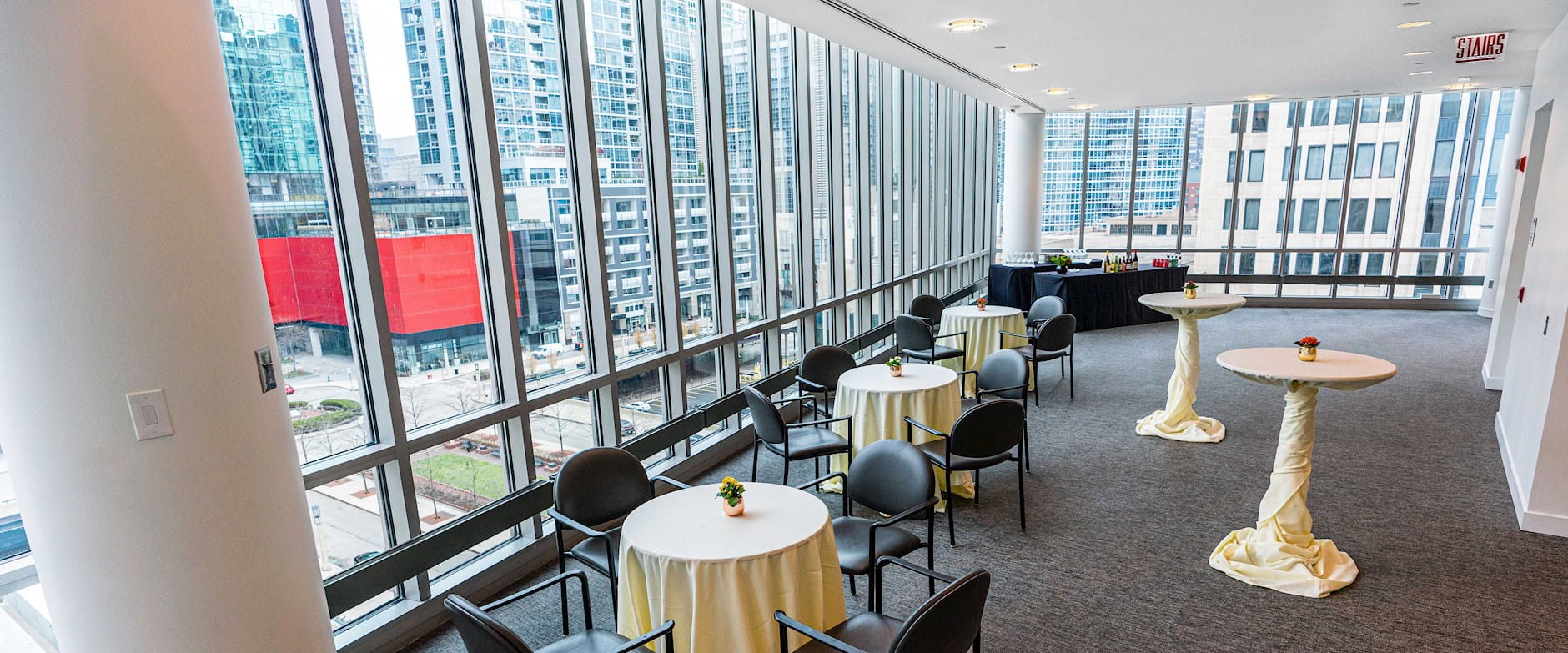 High angle of the Gleacher Center room 650 set with a bar, tables, and chairs